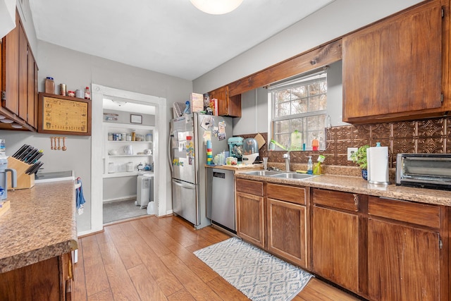 kitchen featuring decorative backsplash, sink, light hardwood / wood-style flooring, and stainless steel appliances