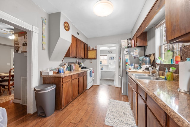 kitchen featuring ceiling fan, electric range, sink, stainless steel refrigerator, and light wood-type flooring