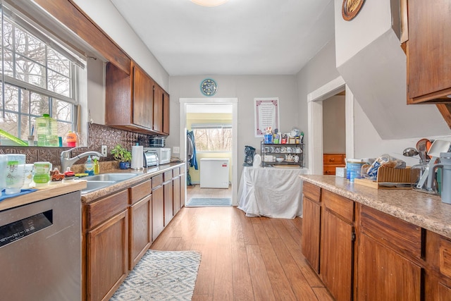 kitchen featuring decorative backsplash, light hardwood / wood-style floors, dishwasher, and sink