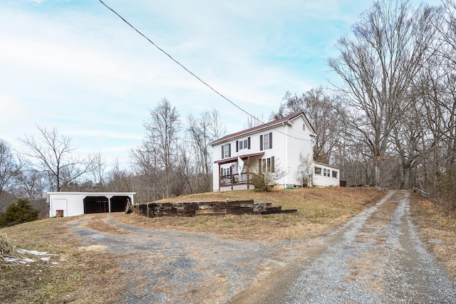 view of side of property with a garage, a porch, a carport, and an outdoor structure