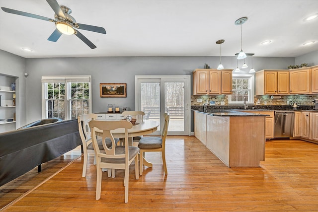 kitchen featuring dishwasher, light brown cabinets, sink, hanging light fixtures, and light wood-type flooring