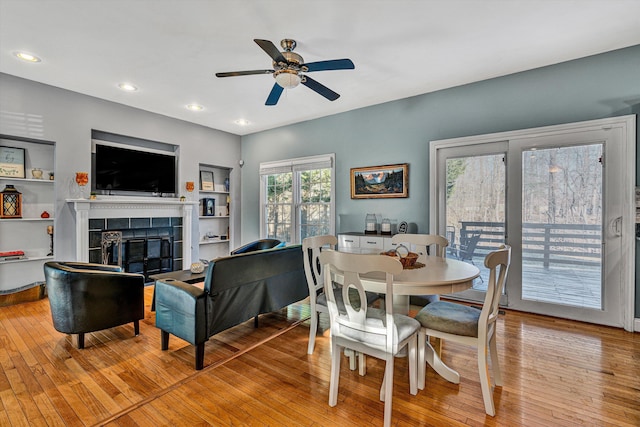 dining area featuring a fireplace, built in features, light hardwood / wood-style flooring, and ceiling fan