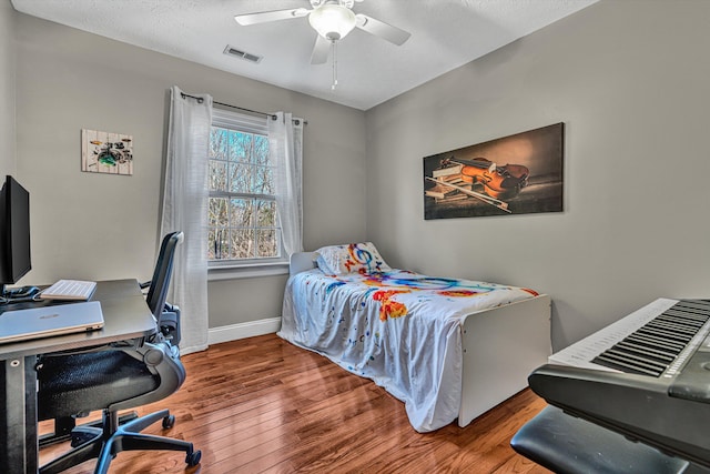 bedroom featuring ceiling fan, hardwood / wood-style floors, and a textured ceiling