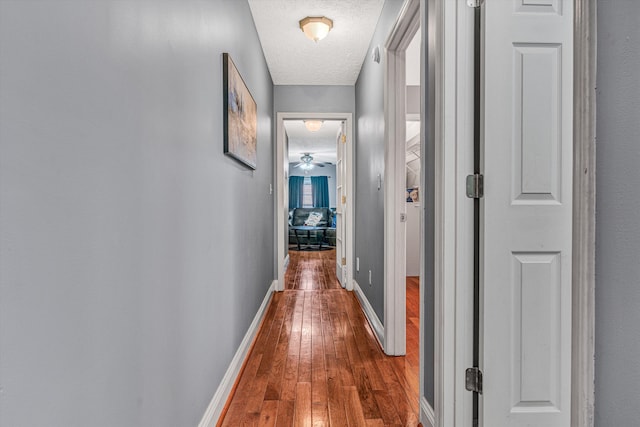 hallway with hardwood / wood-style flooring and a textured ceiling