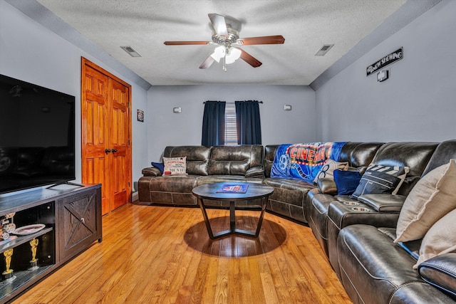 living room with ceiling fan, light hardwood / wood-style floors, and a textured ceiling