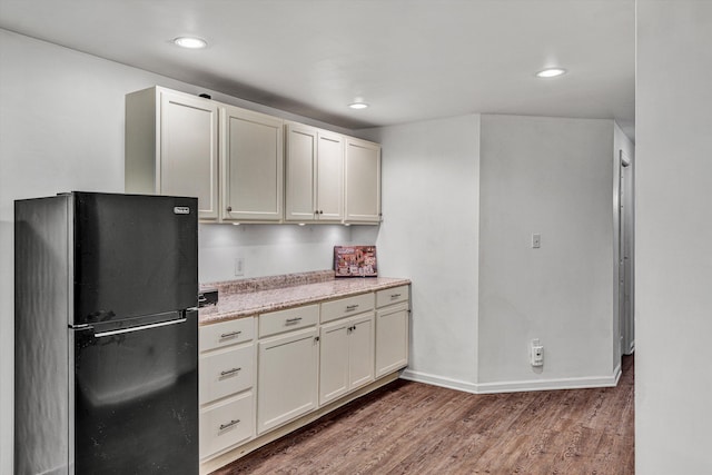 kitchen with black refrigerator, light stone countertops, and dark hardwood / wood-style floors