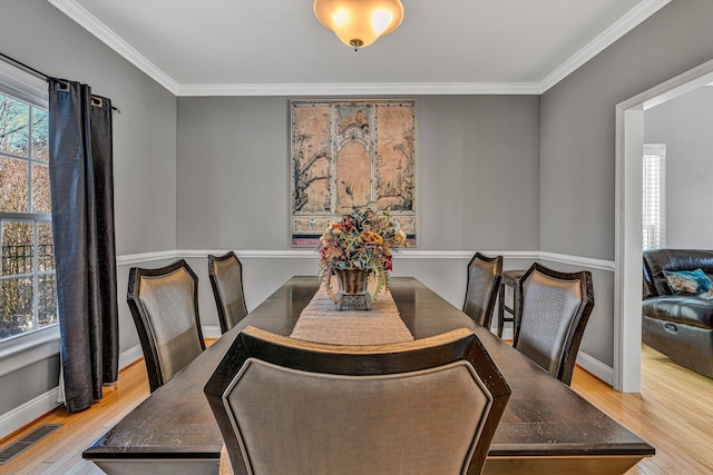 dining area with light hardwood / wood-style flooring and ornamental molding