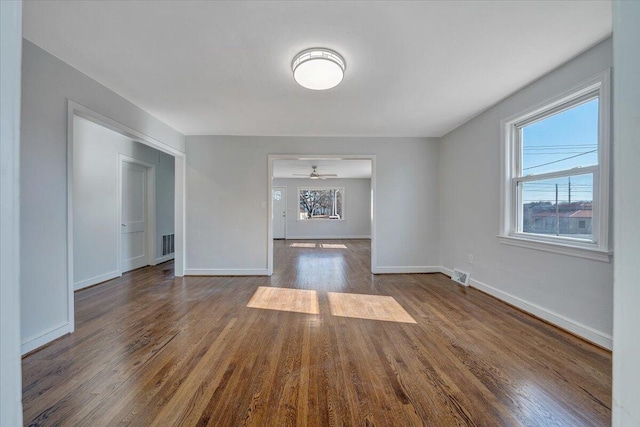 unfurnished living room with dark wood-type flooring and plenty of natural light