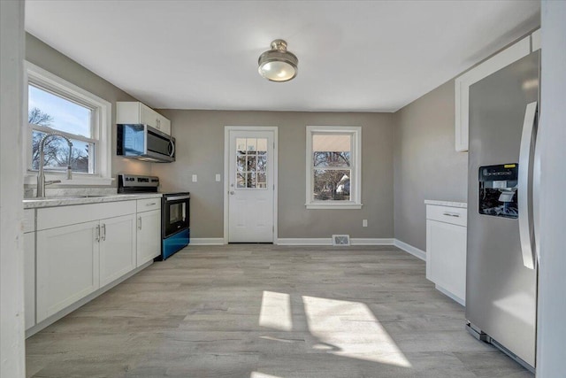 kitchen with light hardwood / wood-style floors, sink, white cabinetry, and stainless steel appliances