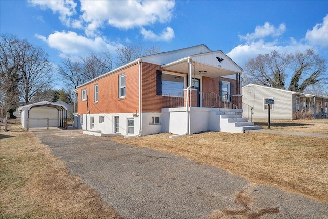 view of front of house featuring a front yard, covered porch, a garage, and an outbuilding