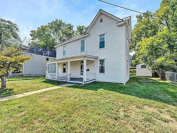 view of front property featuring a front yard, a porch, and a storage unit