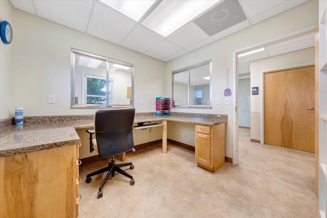 carpeted home office featuring a paneled ceiling and built in desk