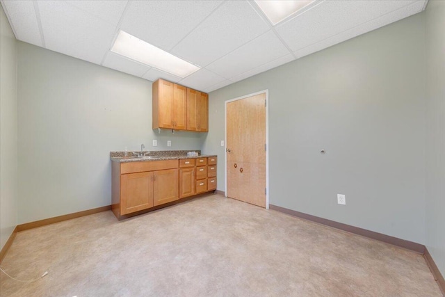 kitchen with light colored carpet, a drop ceiling, and sink