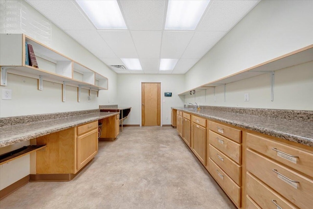 kitchen featuring a paneled ceiling, built in desk, and sink