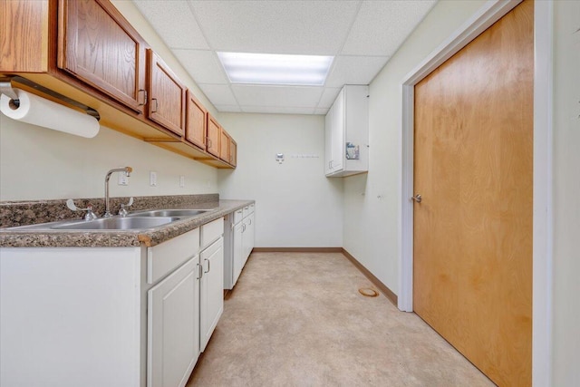 kitchen with light colored carpet, white cabinets, a drop ceiling, and sink