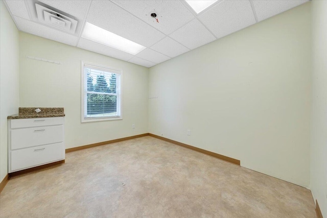 empty room featuring light colored carpet and a drop ceiling