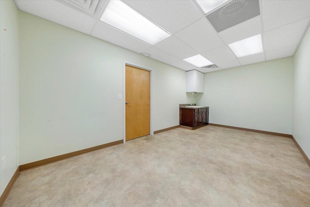 carpeted spare room with a paneled ceiling and sink