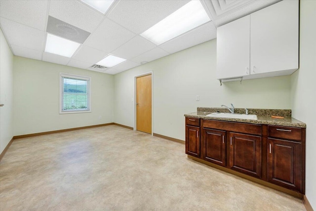 bar with sink, a paneled ceiling, light stone countertops, white cabinets, and dark brown cabinets