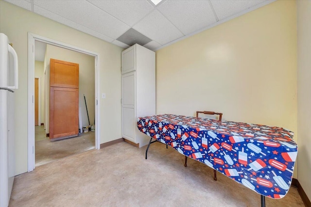 bedroom with a drop ceiling and white fridge