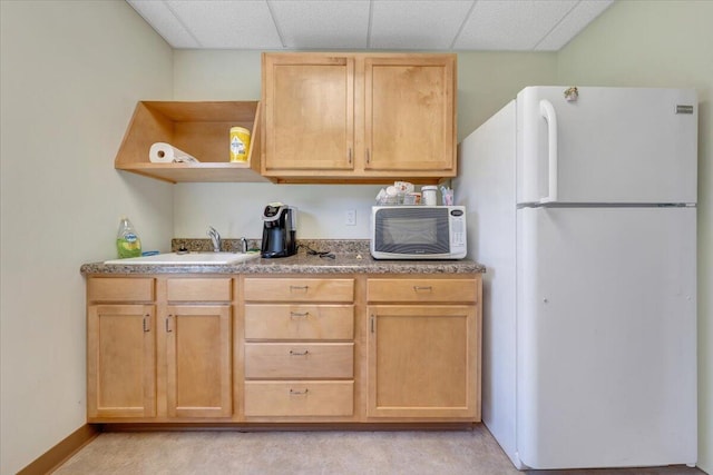 kitchen featuring light brown cabinetry, sink, a paneled ceiling, and white fridge