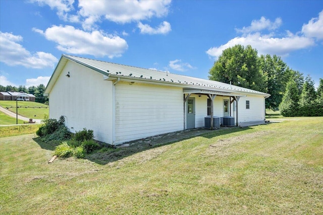 back of property with central AC and a lawn