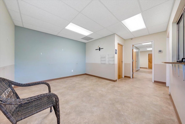 living area featuring a paneled ceiling and light carpet