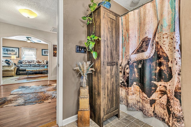 bathroom with ceiling fan and a textured ceiling