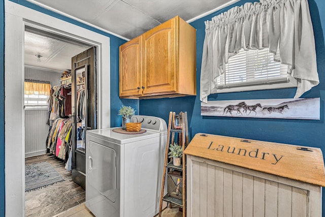 clothes washing area featuring washer / clothes dryer, ornamental molding, and cabinets