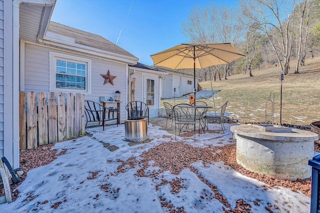 snow covered patio with an outdoor fire pit