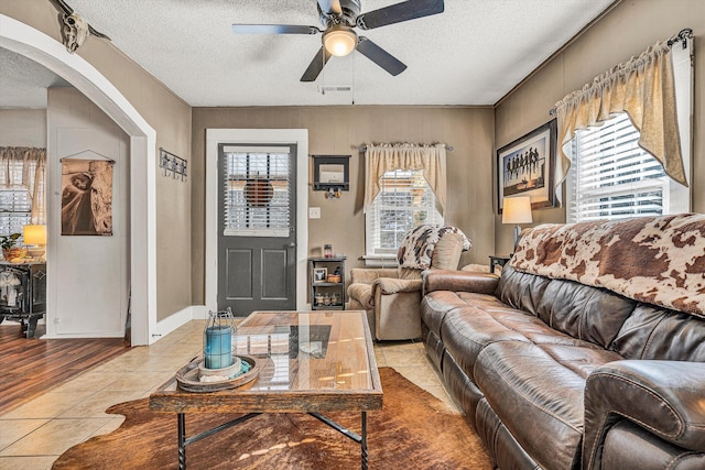 tiled living room with ceiling fan, plenty of natural light, and a textured ceiling