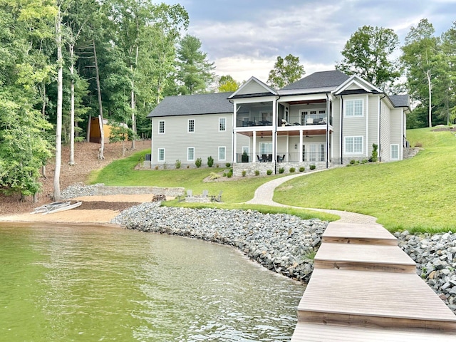 back of house featuring a balcony, a yard, and a water view