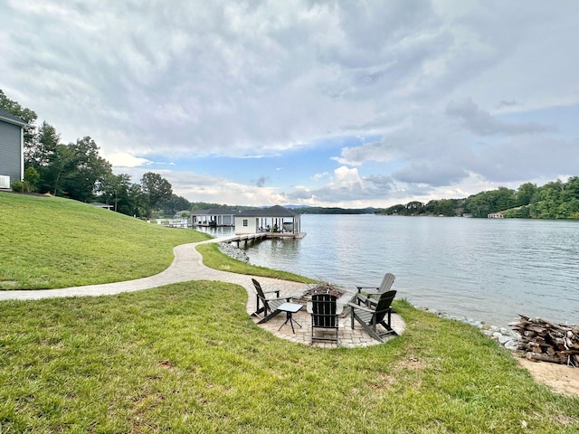 view of dock featuring an outdoor fire pit, a lawn, and a water view