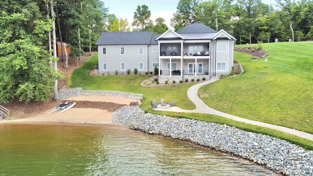 back of house with a balcony, a water view, and a lawn