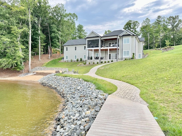 rear view of property with a lawn, a sunroom, and a water view