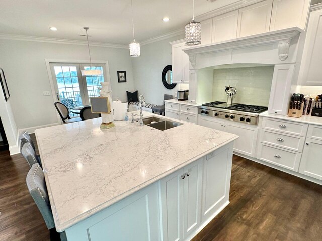 kitchen with light stone counters, hanging light fixtures, stainless steel gas stovetop, and white cabinetry
