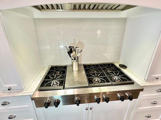 room details featuring extractor fan, white cabinets, decorative backsplash, and stainless steel gas cooktop