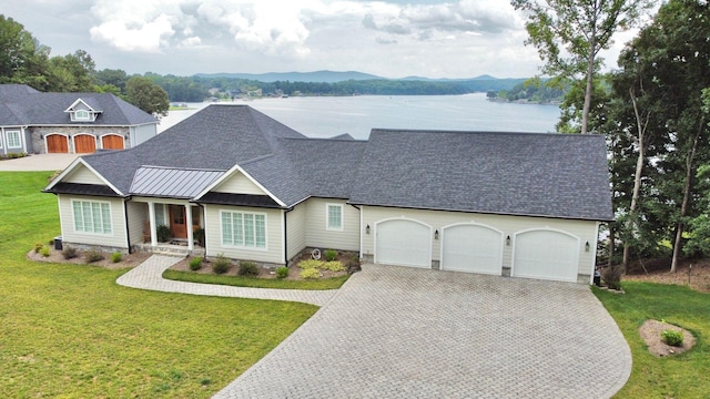 view of front of house with a garage, a front lawn, and a water and mountain view