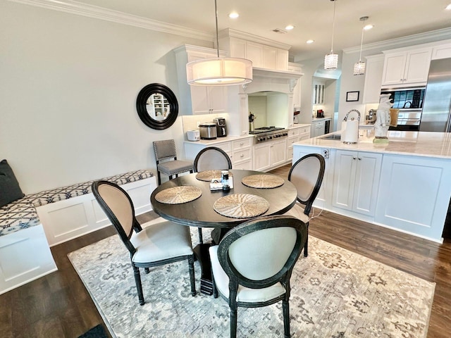 dining space with crown molding, dark wood-type flooring, and sink