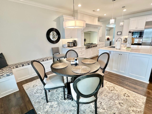 dining room featuring sink, ornamental molding, and dark hardwood / wood-style floors