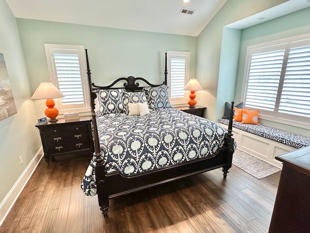 bedroom with multiple windows, lofted ceiling, and hardwood / wood-style floors