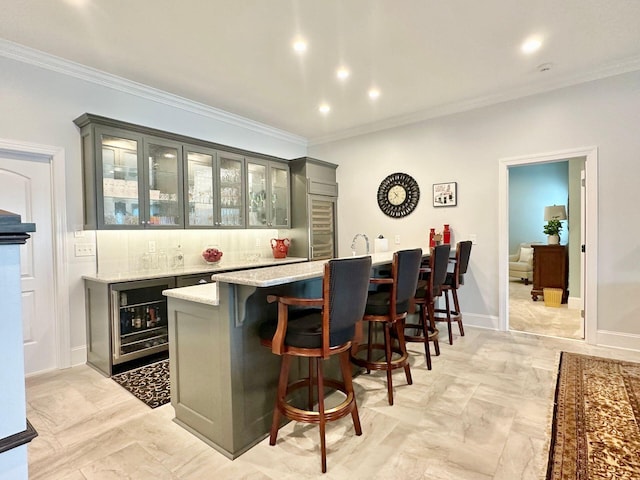 bar with light stone counters, gray cabinetry, crown molding, and wine cooler