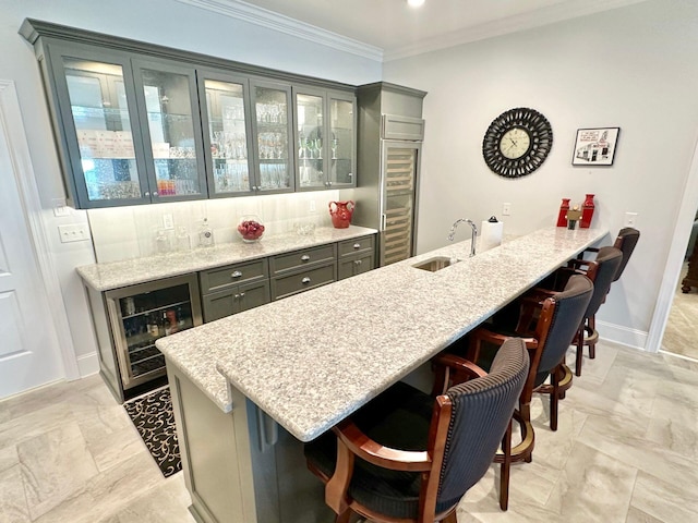 bar with sink, wine cooler, light stone countertops, and ornamental molding