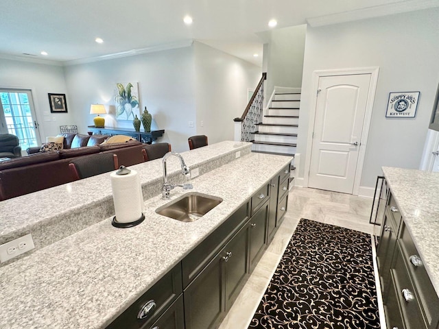 kitchen with sink, light stone counters, and crown molding