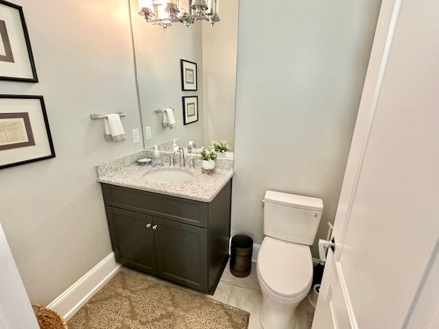 bathroom with vanity, toilet, an inviting chandelier, and tile patterned flooring