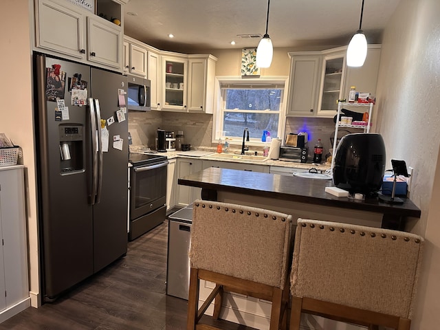 kitchen featuring appliances with stainless steel finishes, pendant lighting, sink, dark hardwood / wood-style flooring, and a kitchen bar