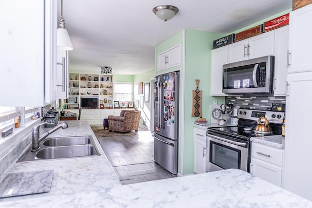 kitchen with light stone counters, sink, white cabinets, and appliances with stainless steel finishes