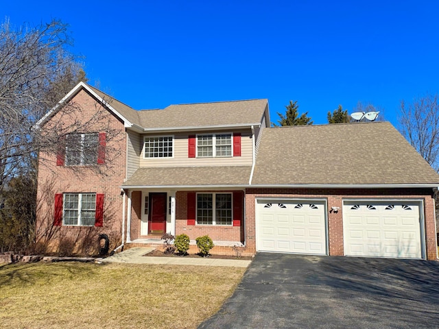 traditional-style house featuring an attached garage, a shingled roof, aphalt driveway, and a front yard