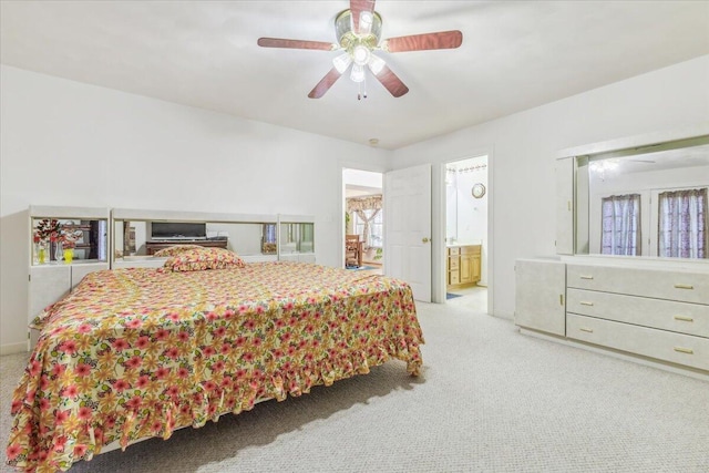 bedroom with light carpet, ensuite bathroom, and ceiling fan