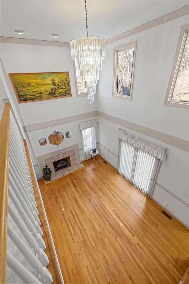 unfurnished living room with a notable chandelier, hardwood / wood-style flooring, radiator heating unit, and a fireplace