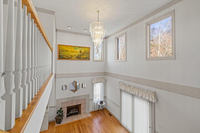 interior space with an inviting chandelier, light hardwood / wood-style flooring, crown molding, and a fireplace